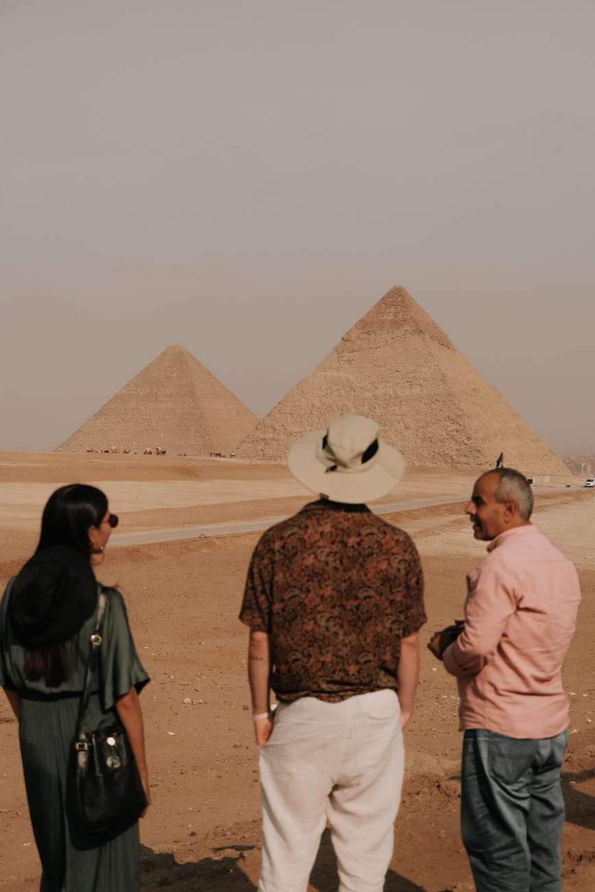 tourists admiring egyptian pyramids while talking with a local man