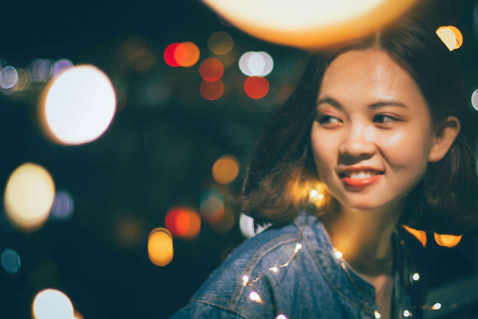 bokeh photography of woman wearing blue denim jacket