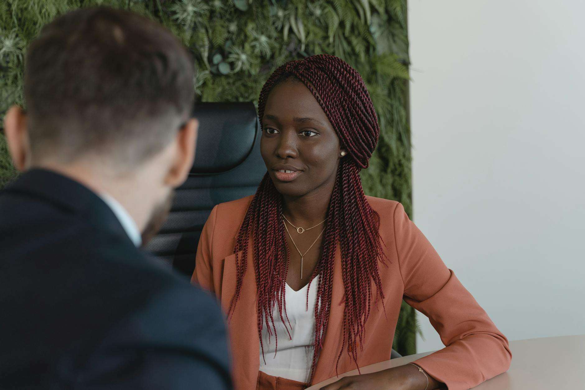 woman in corporate attire sitting on an office chair while listening carefully