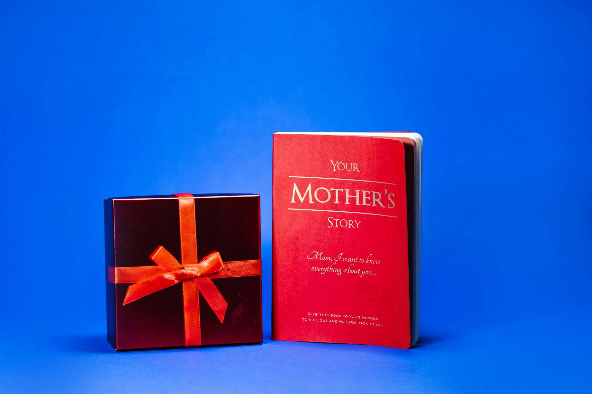 close up shot of a book and a red gift box on a blue surface