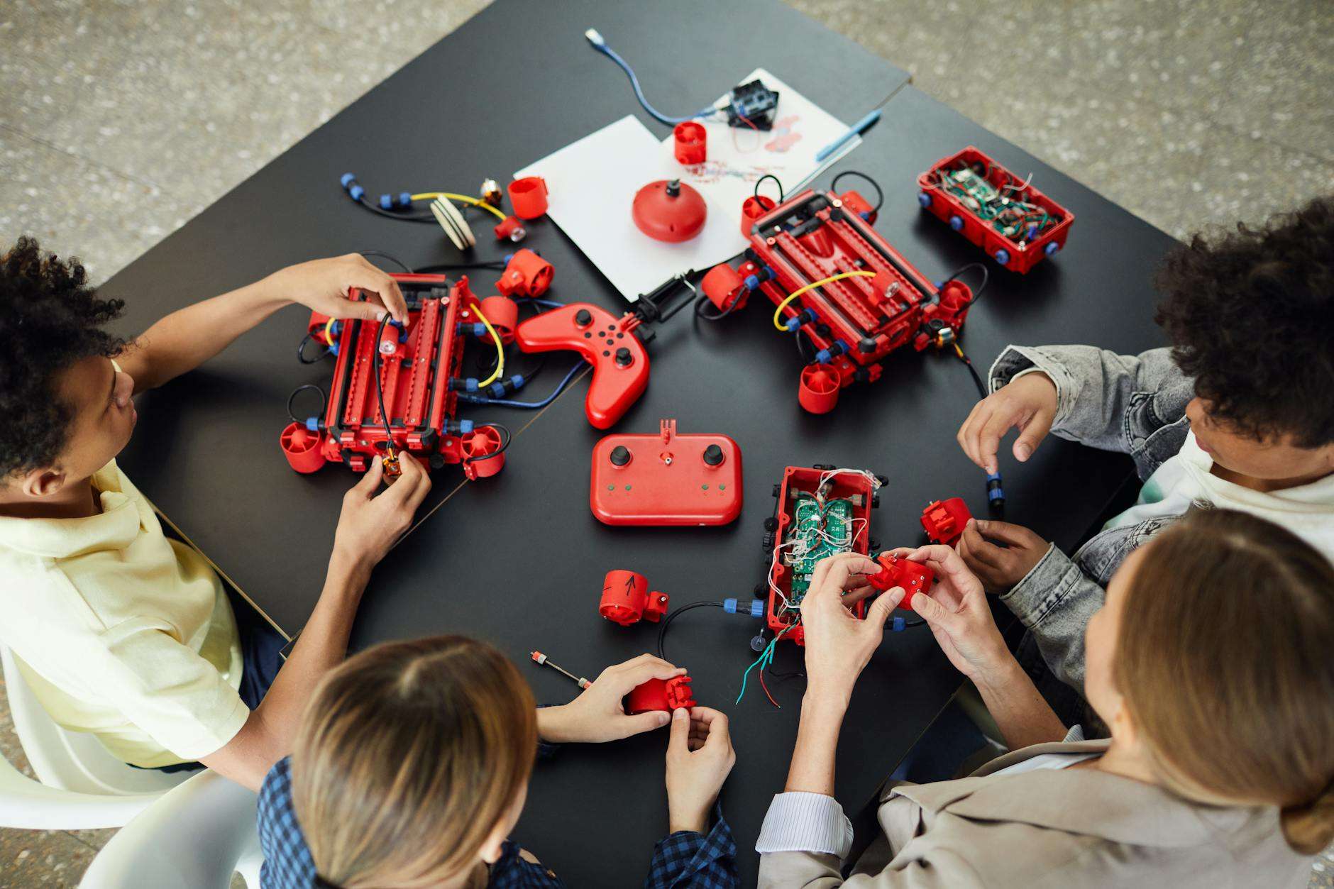 children sitting by table with woman and learning electronics